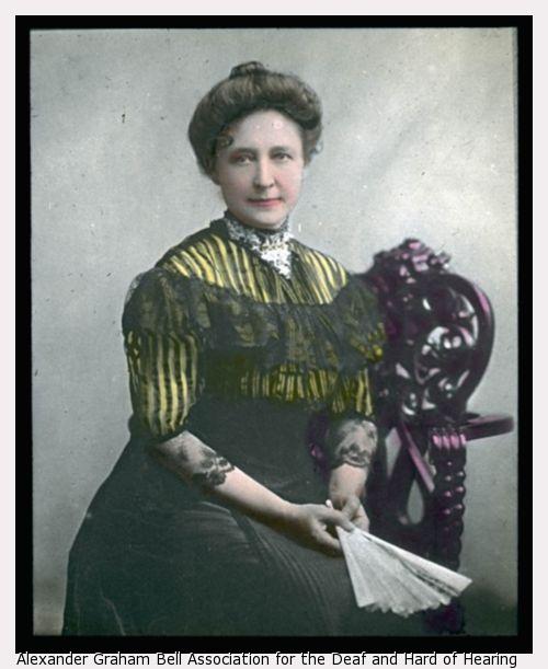 Kate Adams Keller facing right with bun in hair in a color lantern portrait.
