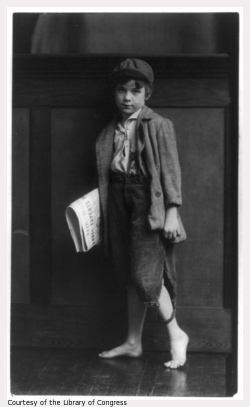 Bare-footed boy holding newspapers.