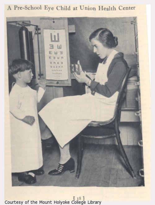 A boy and a woman with eye chart.