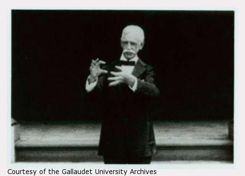 Amos G. Draper stands on a stage signing the charter of Gallaudet College