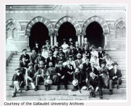 A group of men and women sit on the steps of Chapel Hall at the National Deaf-Mute College ( later renamed Gallaudet University ).