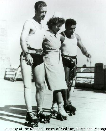 Two veterans with prosthetic legs use a nurse for support as the three rollerskate.