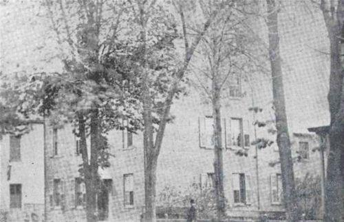 View of large brick house through trees.