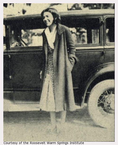 A woman stands next to a car.